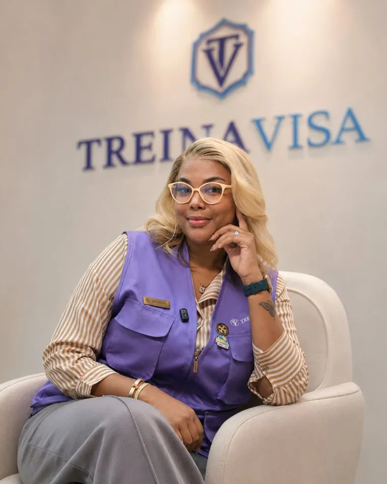 Ester Caiafa sentada em frente ao logo TreinaVISA